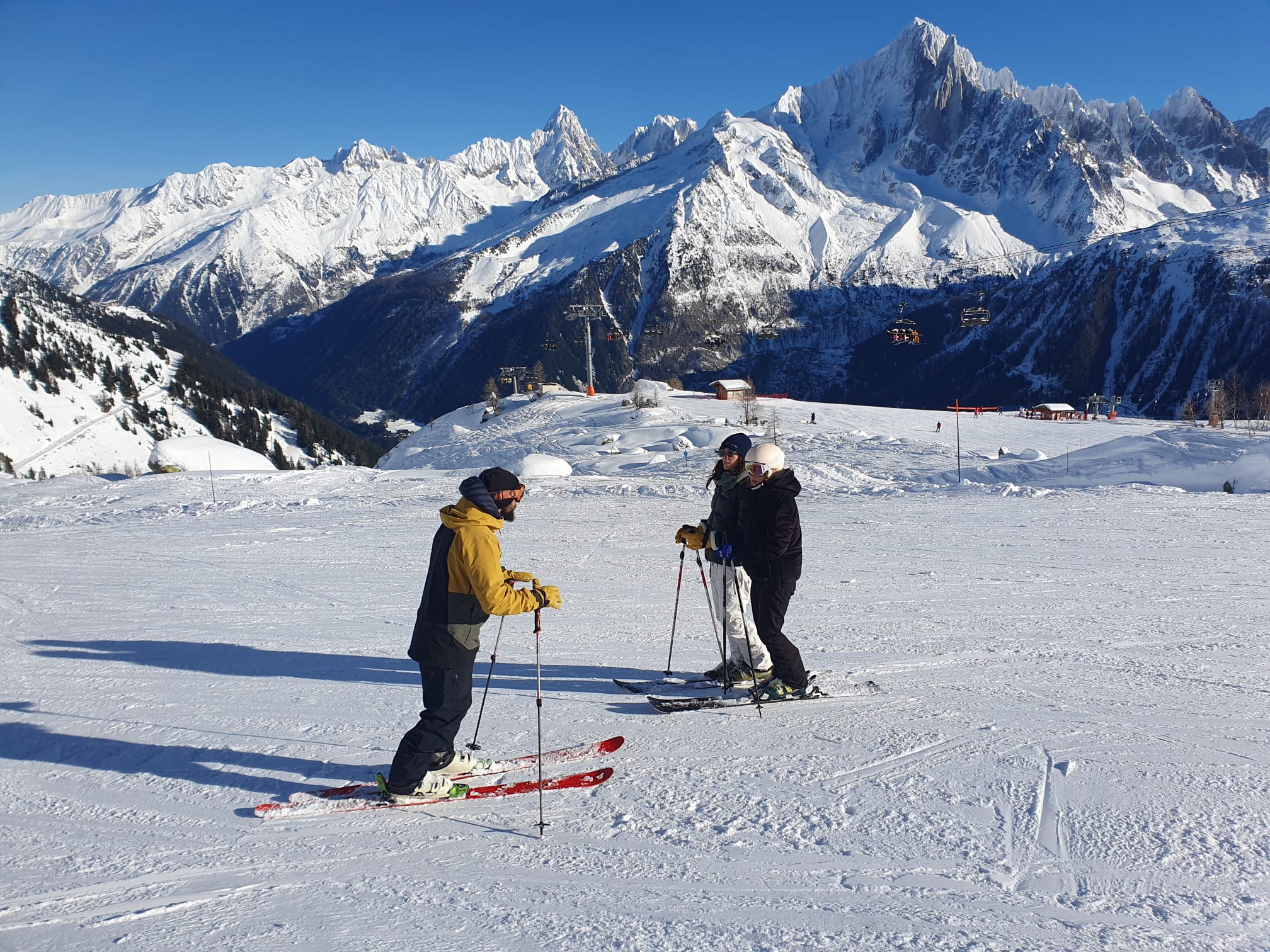 Xavier en veste jaune donnant un cours de ski face aux montagnes de Chamonix
